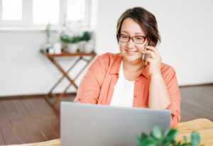 Adult charming brunette woman in glasses plus size body positive working with laptop at the home Perks At Work